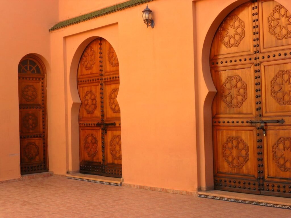 Portes en bois sculpté d'une demeure marocaine, illustrant l'ouverture de la Maison Zintiya sur le patrimoine du soin marocain.